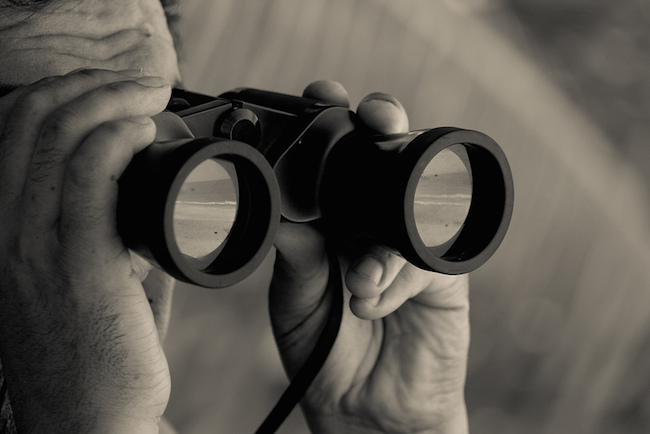 a close-up image of a man looking through binoculars