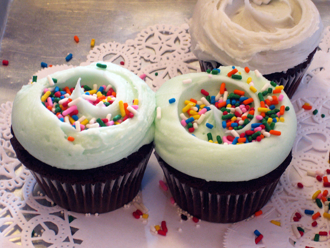chocolate cupcakes with white frosting and rainbow sprinkles