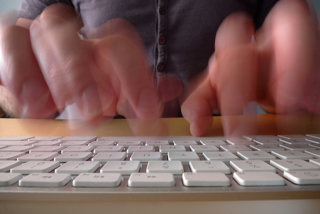 fingers in motion typing fast on a keyboard